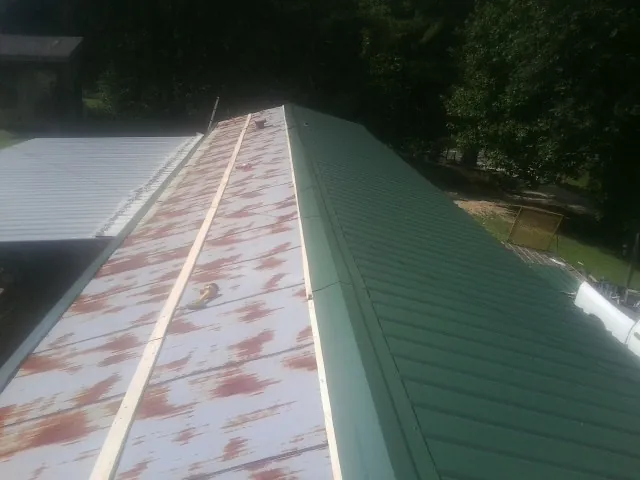 Old rusted panels beside newly installed green metal roofing — Wind Damage Roof Repair by Roofing Brothers in Gautier