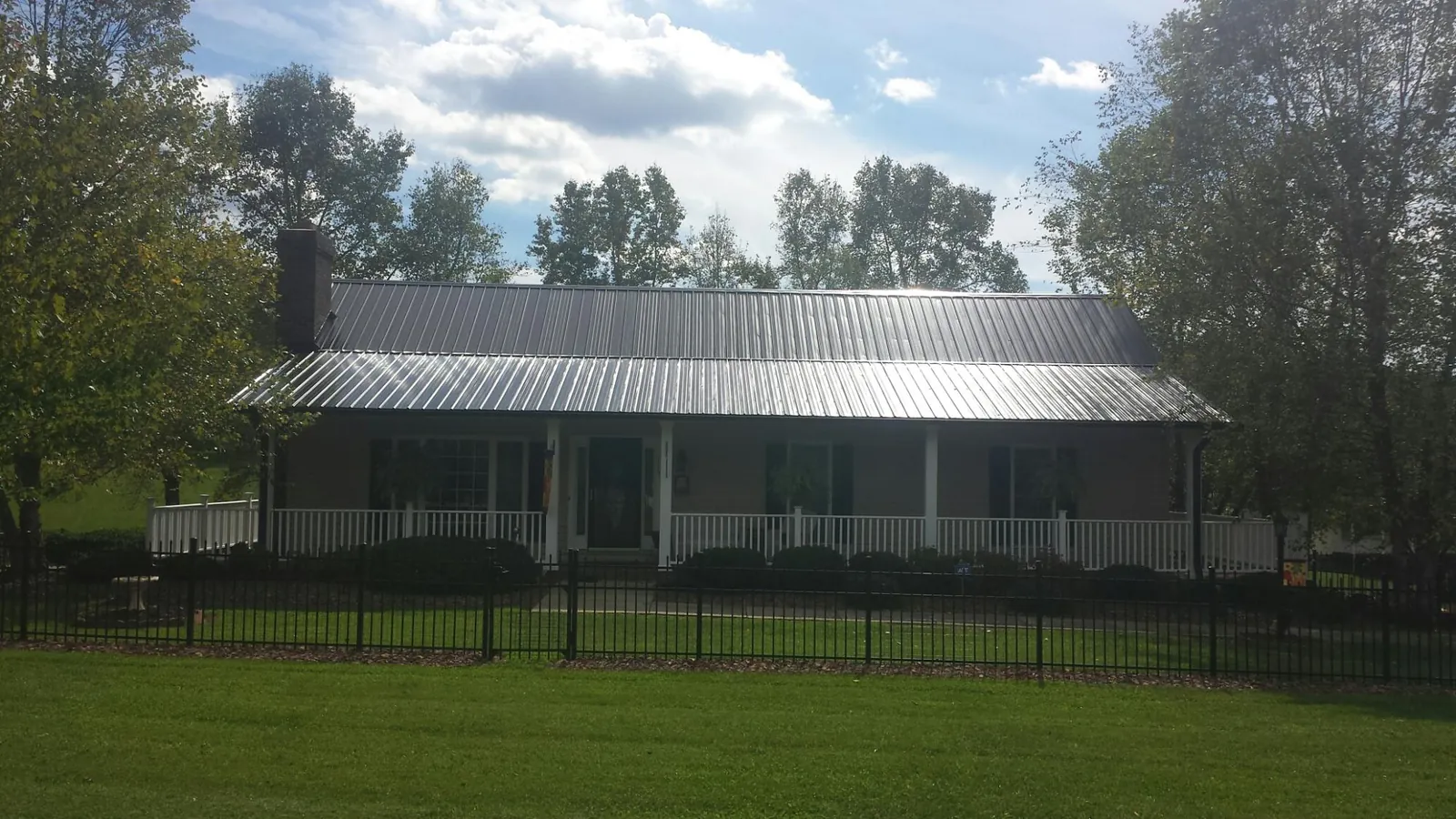 Gray metal roof on a brick ranch with a full width front porch — Gutter Guard Installation work by our crew in Gautier