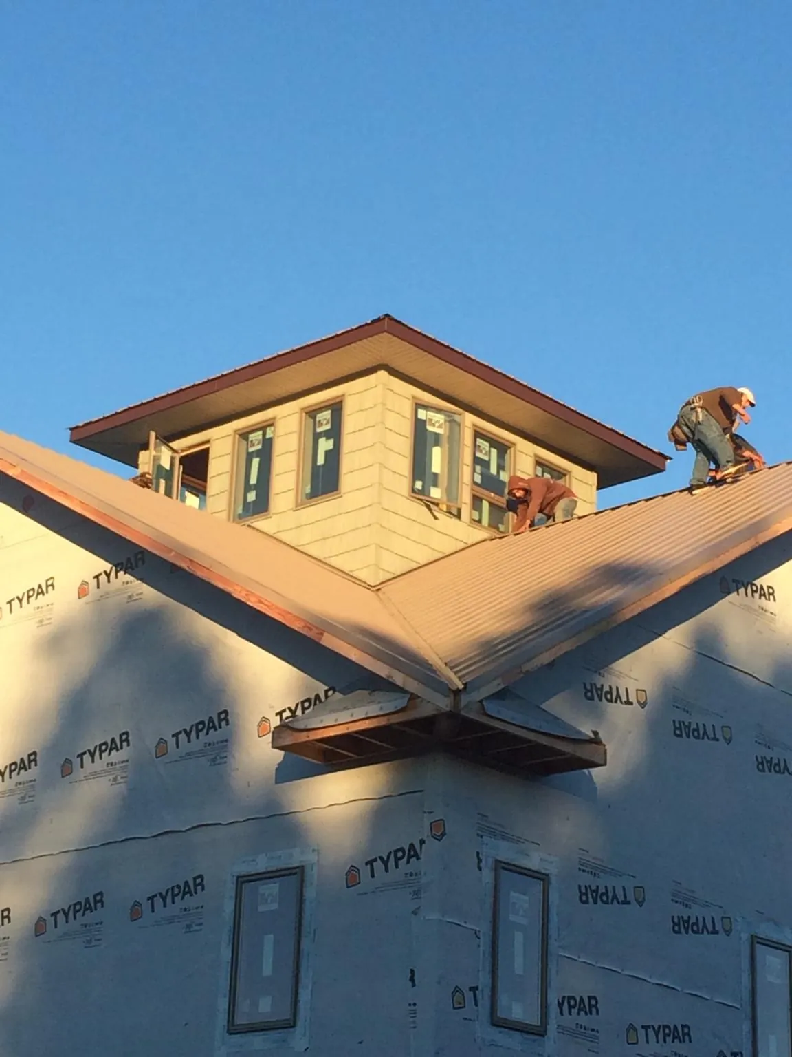 Roofers working around a rooftop cupola on a new metal roof at sunset — Roof Waterproofing in Gautier by Roofing Brothers